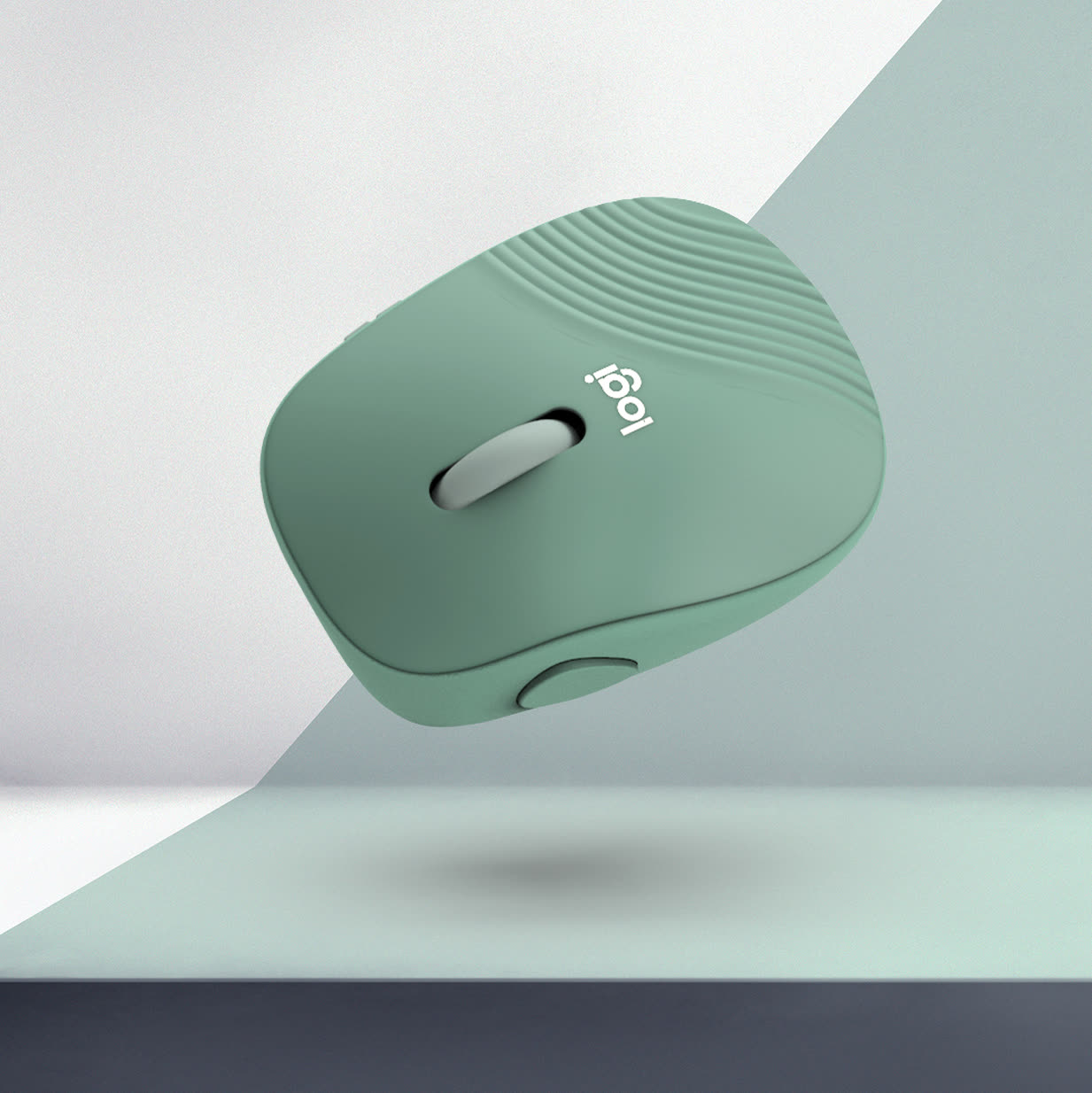 Sage-green Logitech mouse floating above a pale surface