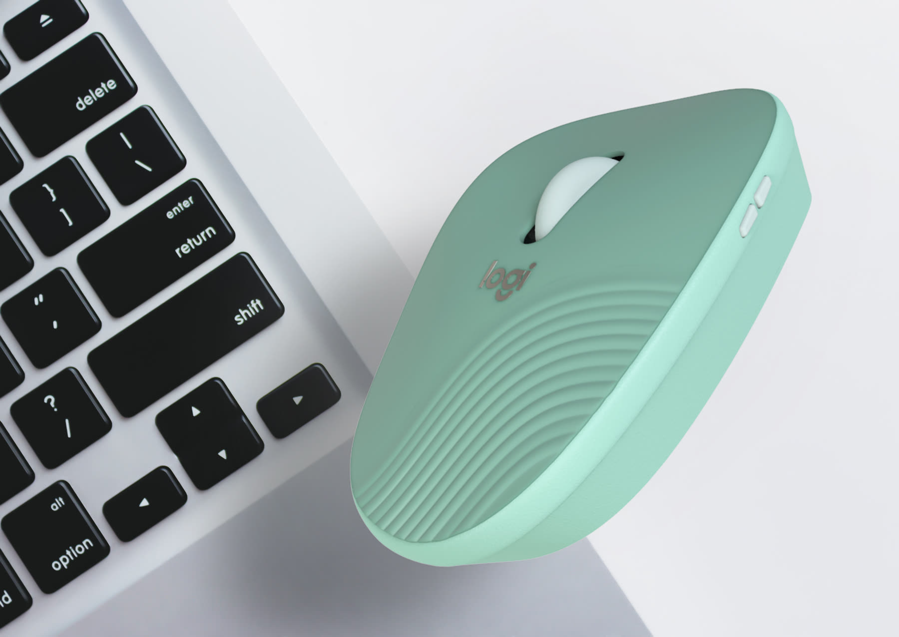 Mint Logitech mouse resting against a laptop keyboard